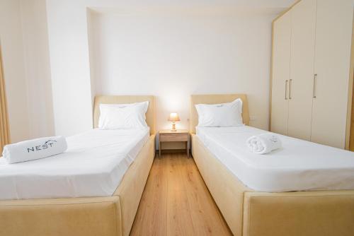 two twin beds in a room with a night stand at Poseidon Nest - 2BR, 360 Sea View, Office, Pool in Durrës