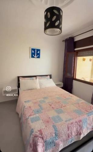 a bedroom with a bed with a quilt on it at Firras Mdiq in M'diq