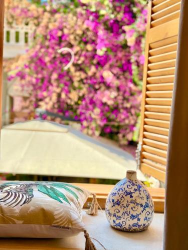 a vase sitting on a table next to a window with flowers at Old Town Suites Muradie in Vlorë
