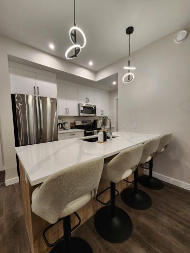 a kitchen with a large white counter and chairs at Riverstone Retreat in Golden BC in Golden