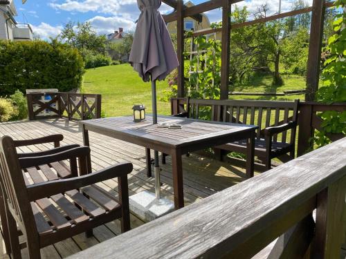 a wooden table and chairs on a deck with an umbrella at Ella's House - Central Bengtsfors Stay in Bengtsfors