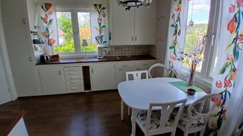 a kitchen with a white table and chairs and windows at Ella's House - Central Bengtsfors Stay in Bengtsfors