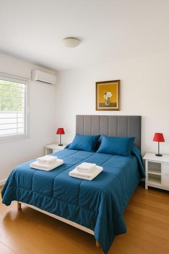 a bedroom with a blue bed with two towels on it at Alojamiento H346 in Tandil