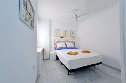 a white bedroom with a bed with blue pillows at Paraíso del Sol in Salobreña