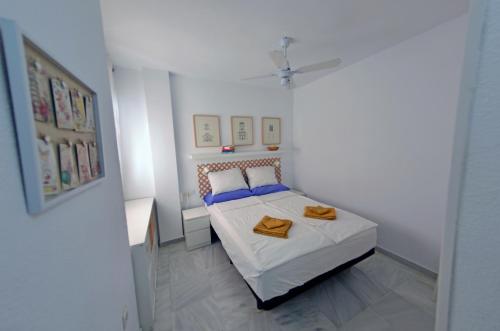 a white bedroom with a bed with two towels on it at Paraíso del Sol in Salobreña