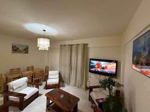 ein Wohnzimmer mit einem Flachbildfernseher an der Wand in der Unterkunft Villa in Marseille Beach 2 BOHO STYLE in El-Alamein