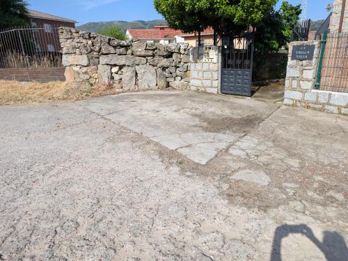 a driveway with a stone wall and a gate at la erilla vieja in Navarrevisca