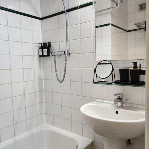 une salle de bain carrelée blanche avec une douche et un lavabo dans l'établissement Charming Studio near La Defense, à Courbevoie