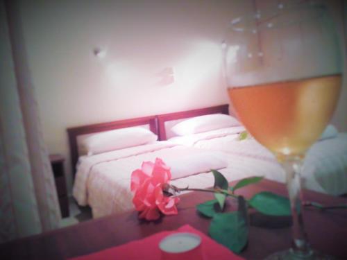 a glass of wine on a table next to a bed at Georgia Apartments in Roda