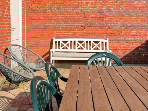 a wooden table and chairs with a bench in a brick wall at 6 person holiday home in R m in Sønderby