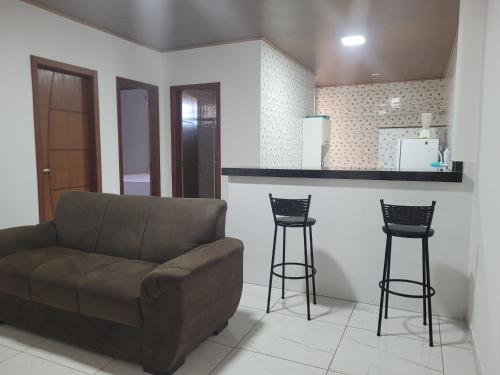 a living room with a couch and two bar stools at Apartamento com ar e exclusivo, zona sul de Ilhéus, bairro Hernani Sá in Ilhéus