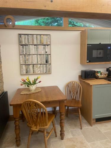 a kitchen with a wooden table and two chairs at Tawny Lodge, Evesham Nr Cotswolds in Evesham