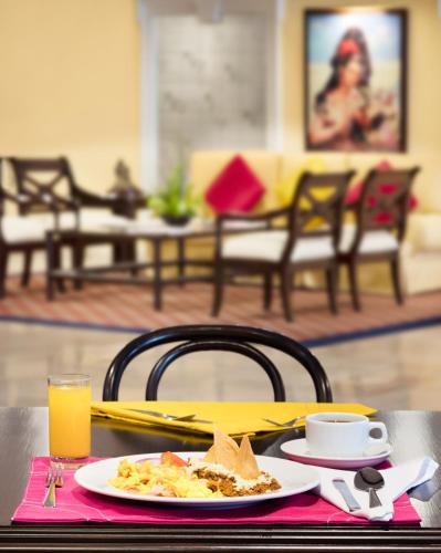 a table with a plate of food and a cup of orange juice at Hotel Francia Aguascalientes in Aguascalientes