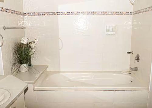 a white bathroom with a tub and a vase of flowers at New ! Beachfront Villa - Golf, Pool & Ocean View in Dorado