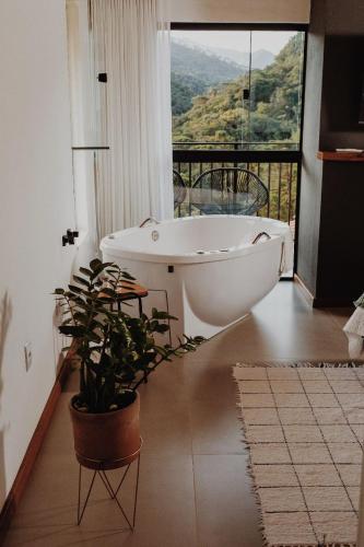 a bathroom with a tub and a potted plant at Encontro dos Vales in Visconde De Maua