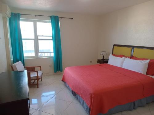 a bedroom with a red bed and a window at Alleyne Apartments in Bridgetown