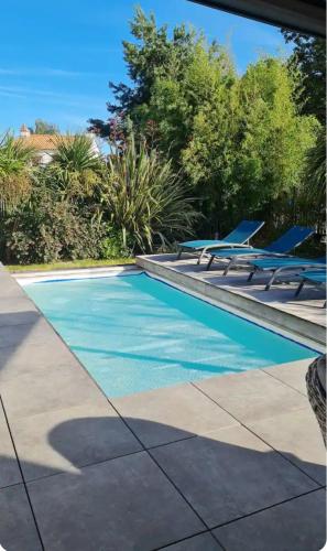une piscine avec des chaises longues à côté dans l'établissement Joli Appartement de plain-pied, à Pornic