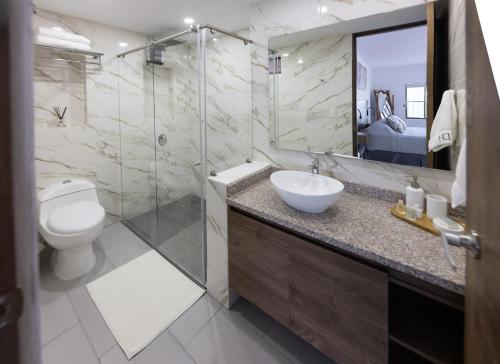 a bathroom with a sink and a toilet and a mirror at Doral House Villavicencio in Villavicencio