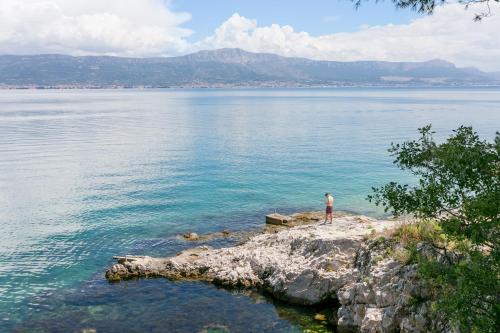 a man standing on the edge of a large body of water at Apartments with parking space Slatine, Ciovo - 24699 in Slatine