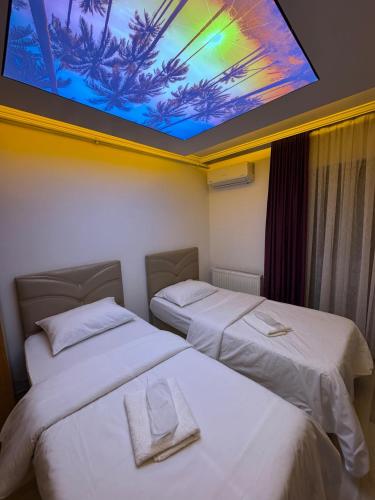 two beds in a room with a large tv on the ceiling at Uluhan Suite Otel in Bostancı