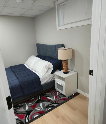 a bedroom with a bed and a lamp on a rug at Cozy 2 bedroom basement with side entrance in Bélanger