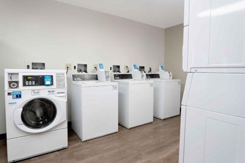 a laundry room with four washing machines and a refrigerator at Extended Stay America Suites - Fort Lauderdale - Cypress Creek - NW 6th Way in Fort Lauderdale