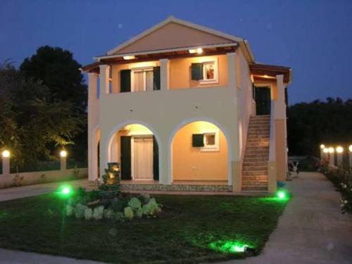 a large house with lights in the yard at night at Georgia Apartments in Roda