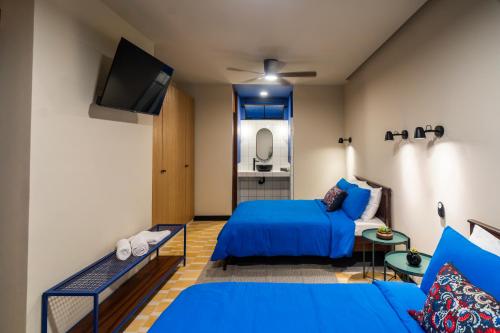 a bedroom with a blue bed and a tv at Ginger Banana Hostel in Oaxaca City