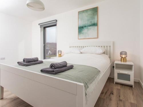 a white bedroom with a large bed with towels on it at Faodail in Portree