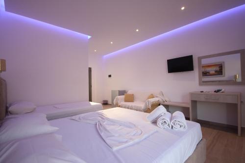 a white room with a bed and a tv at Bujtina Eleni in Himare