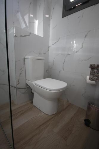 a white toilet in a bathroom with marble walls at Bujtina Eleni in Himare