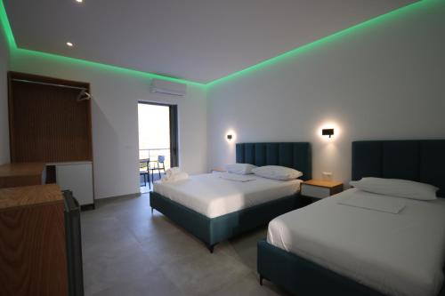 a hotel room with two beds and a balcony at Bujtina Eleni in Himare