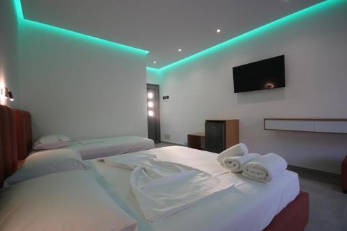 a room with two beds and a flat screen tv at Bujtina Eleni in Himare