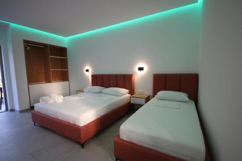 two beds in a hotel room with green lighting at Bujtina Eleni in Himare