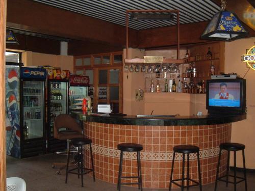 a bar in a restaurant with stools and a television at Hotel Mediterraneo Plaza in San Salvador