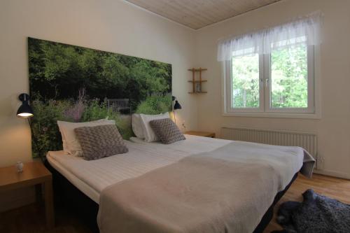 ein Schlafzimmer mit einem großen Bett mit einem großen Gemälde an der Wand in der Unterkunft Snäck Annex in Visby