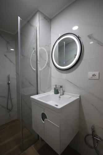 a white bathroom with a sink and a mirror at Bujtina Eleni in Himare