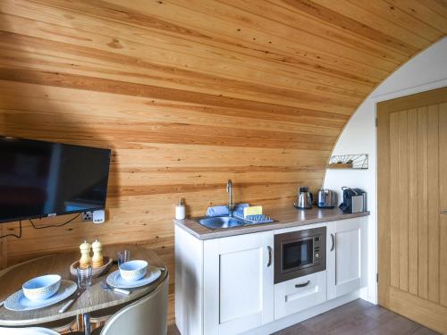 a kitchen with wooden walls and a table and a sink at Sunset Holiday Pod - Uk48592 in Church Stretton