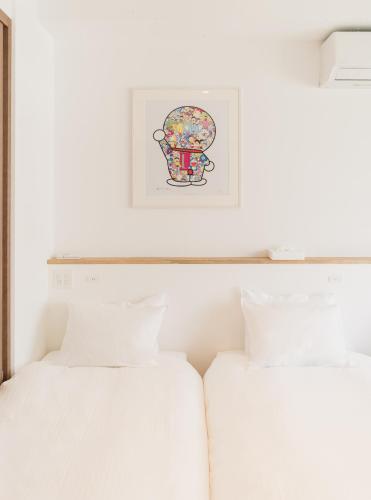 two beds in a bedroom with a picture on the wall at Flower Base HIMAWARI in Fukuoka