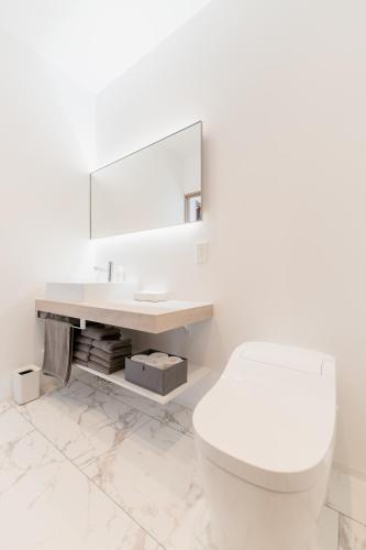 a white bathroom with a toilet and a mirror at Flower Base HIMAWARI in Fukuoka