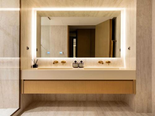 une salle de bain avec un lavabo avec un grand miroir dans l'établissement Luxury flat -3BR 8P- Madeleine Saint Honore, à Paris