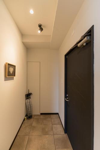 a hallway with a black door and a tile floor at Flower Base HIMAWARI in Fukuoka