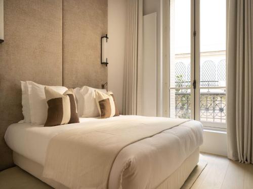 une chambre avec un grand lit blanc avec une fenêtre dans l'établissement Luxury flat -2BR 6P- Madeleine Saint Honore, à Paris