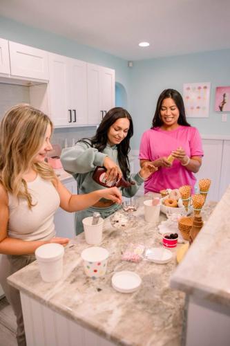 a group of women standing around a counter in a kitchen at Cozy 3BD ‘Sweet Memories’ | Pool, Games & Hot Tub in Cedar Hammock