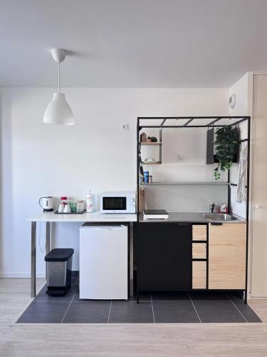 Il comprend une cuisine équipée d'un comptoir noir et d'un réfrigérateur blanc. dans l'établissement Just Sleeping, à Chessy