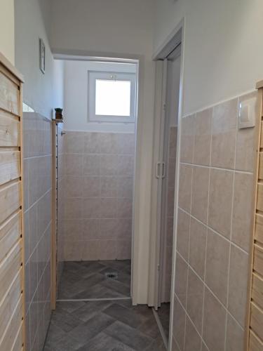 a bathroom with a shower stall and a window at Igali Varázs Apartman 150 méter a fürdőtől in Igal
