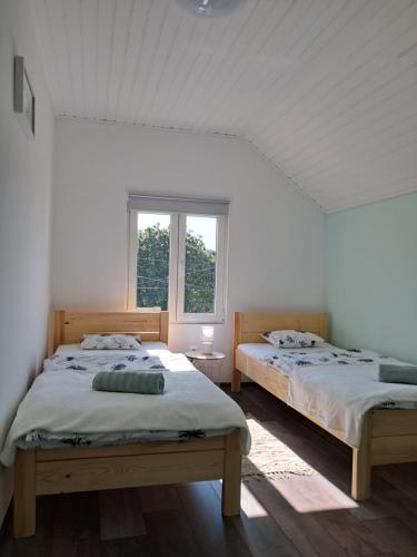 two beds in a white room with a window at Igali Varázs Apartman 150 méter a fürdőtől in Igal