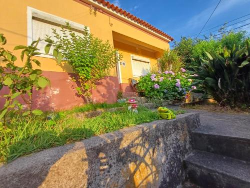 a yellow house with a bird sitting in the grass at Casa da Tia Lena in Coimbra