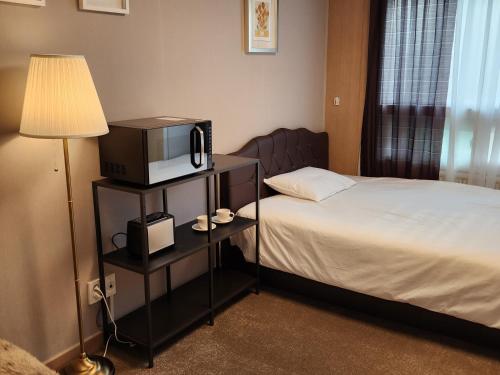 a hotel room with a bed and a tv and a lamp at The BIUMO in Seoul