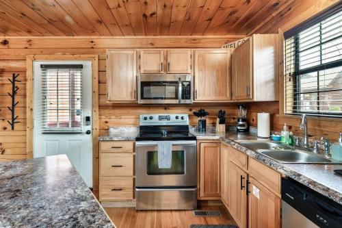 a kitchen with wooden cabinets and a stove top oven at Kate's Cabin - 3 min to Dollywood! Cabin with Hot tub, Game Room, and Resort Pool! in Sevierville
